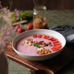 Erdbeer-Smoothie-Bowl mit Nüssen, Beeren und Minze serviert in einer Schale