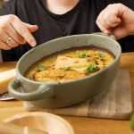 Ofenfrischer OnePot Pesto-Sahne-Lachs in einer Auflaufform, serviert mit goldbraunem Käse