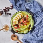 Grüne Smoothie-Bowl mit Banane, Granola und Cranberries