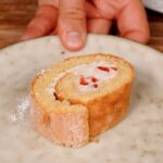 Eine Scheibe Biskuitrolle mit Erdbeerfüllung auf einem Teller